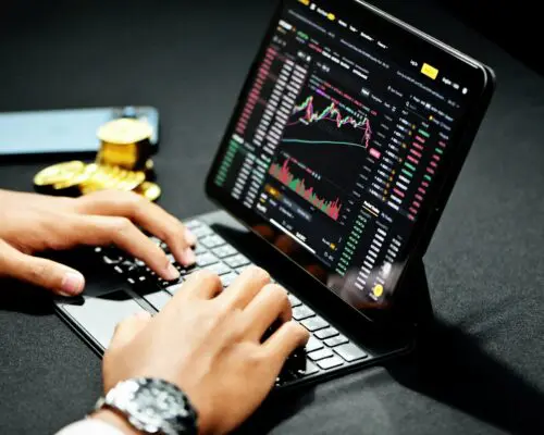 A man typing on a keyboard to check cryptocurrency holdings on a monitor.