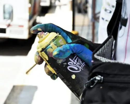 A gloved hand holding a spray can.