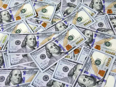 An abundance of one hundred dollar bills spread out across a flat surface.