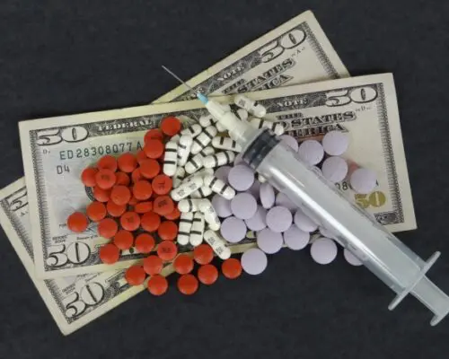 An assortment of cash drugs and needles.