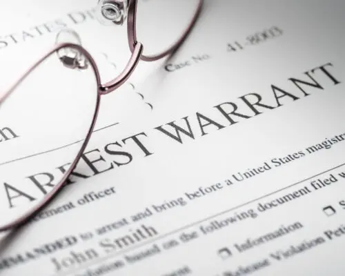 Arrest Warrant document with reading glasses