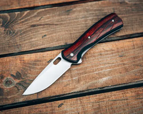 Folding pocket knife with wooden handle. A small knife on a wooden surface.