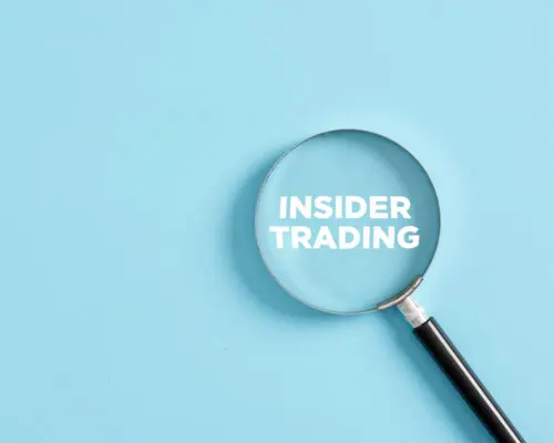 Magnifier with the text insider trading on blue background. Business concept.