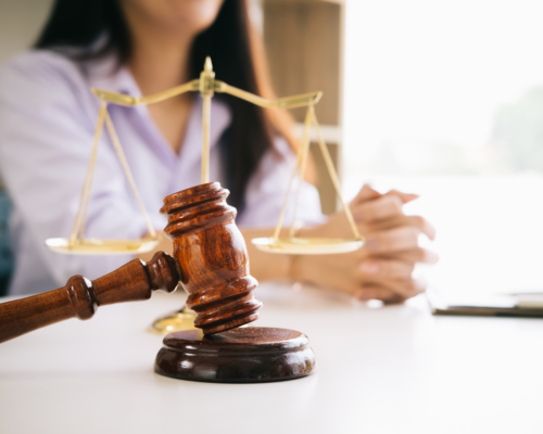 A lawyer sitting at a desk with a gavel and scale of justice on it.