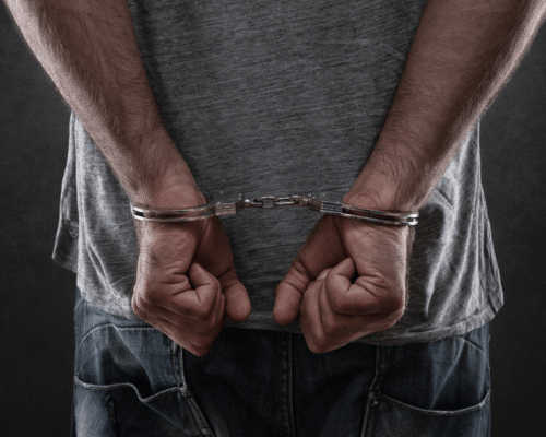 Rear view of man in casual clothing with hands cuffed behind his back, highlighting the seriousness of criminal charges and the importance of strong legal defense strategies