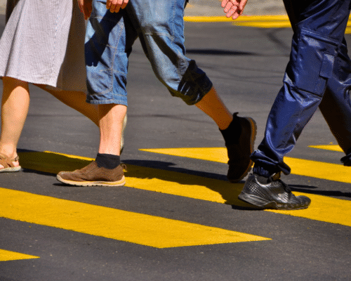 People’s legs walking across a marked crosswalk on a city street, illustrating pedestrian traffic and legal risks in Los Angeles pedestrian accident and vehicular manslaughter cases.