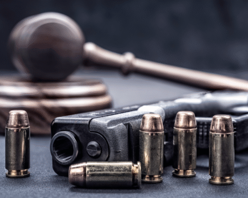 Judge's gavel, handgun, and ammunition representing criminal firearm charges, alleged straw purchasing, and gun crime defense under California and federal law.